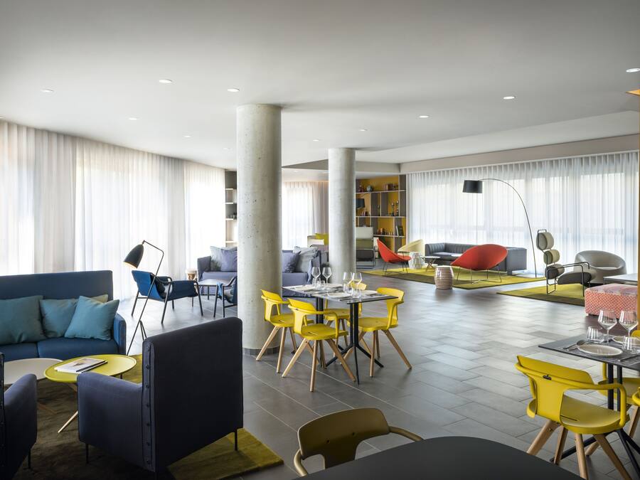 A modern interior with a blue sofa, yellow chairs, and a dining area.