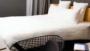 A modern hotel room with a bed, a desk, and a chair. There is a window with a view of mountains. - OKKO Hotels Grenoble Centre (Grenoble)
