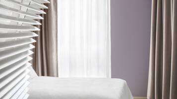 A hotel room with a bed, a suitcase, and a chair.
