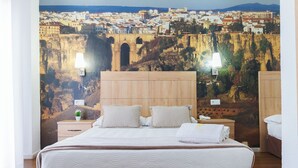 Habitación de hotel con cama, cabecera de madera, dos lámparas de noche, mesita de noche y un gran mural con un paisaje urbano.