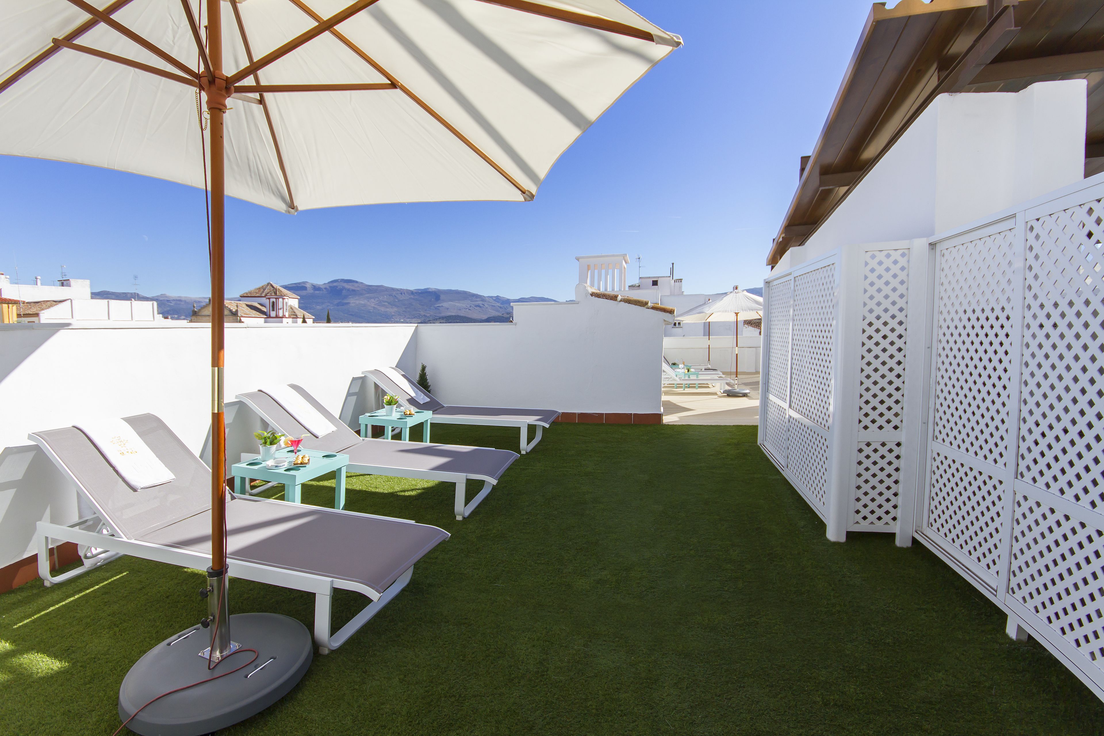 Une terrasse sur le toit, avec des chaises longues, un parasol et une vue sur les montagnes.