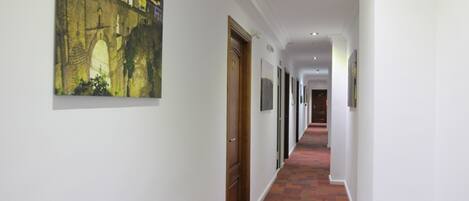 A hallway with a patterned carpet, a framed picture on the wall, and a door with the number 112.