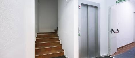 A staircase leading to an elevator, a door labeled 'SALIDA', and a carpeted floor.