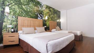 Camera da letto con due letti, testiere in legno, un comodino e un murale raffigurante alberi.