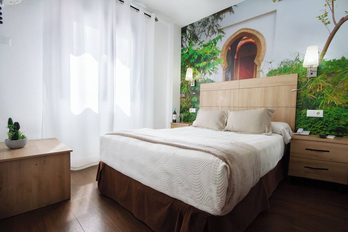 Ein Schlafzimmer mit einem großen Bett, einem Holzkopfstück, Nachttischen und einer Wandmalerei.