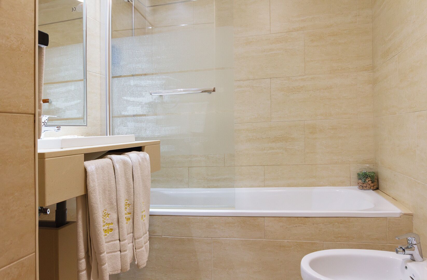 A bathroom with a bathtub, a sink, a mirror, and a towel rack.
