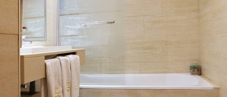 A bathroom with a bathtub, a sink, a mirror, and a towel rack.