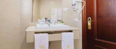 A bathroom with a sink, mirror, towel rack, and a hairdryer on the wall.