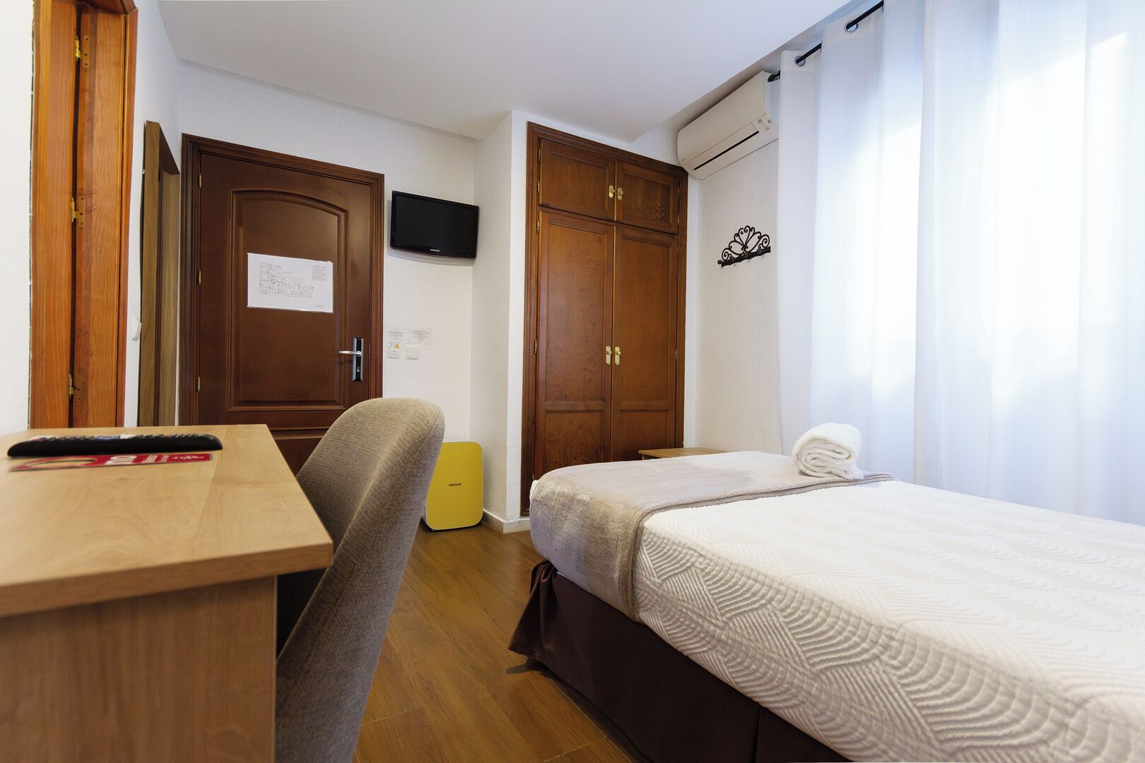 Une chambre comprenant un lit, un bureau, une chaise, une télévision et une armoire.