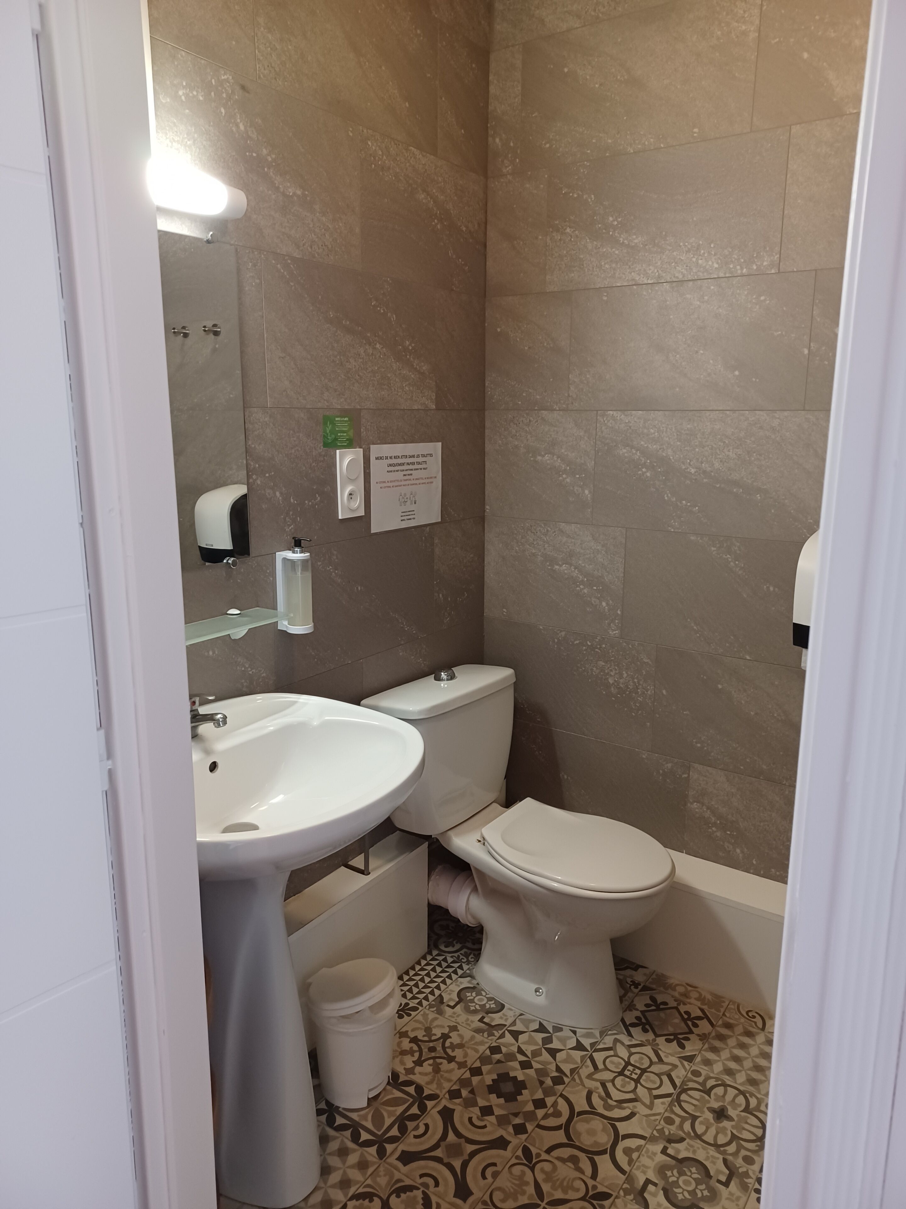 Un baño con inodoro, lavamanos y secamanos.