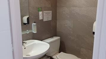 Un baño con inodoro, lavamanos y secamanos.