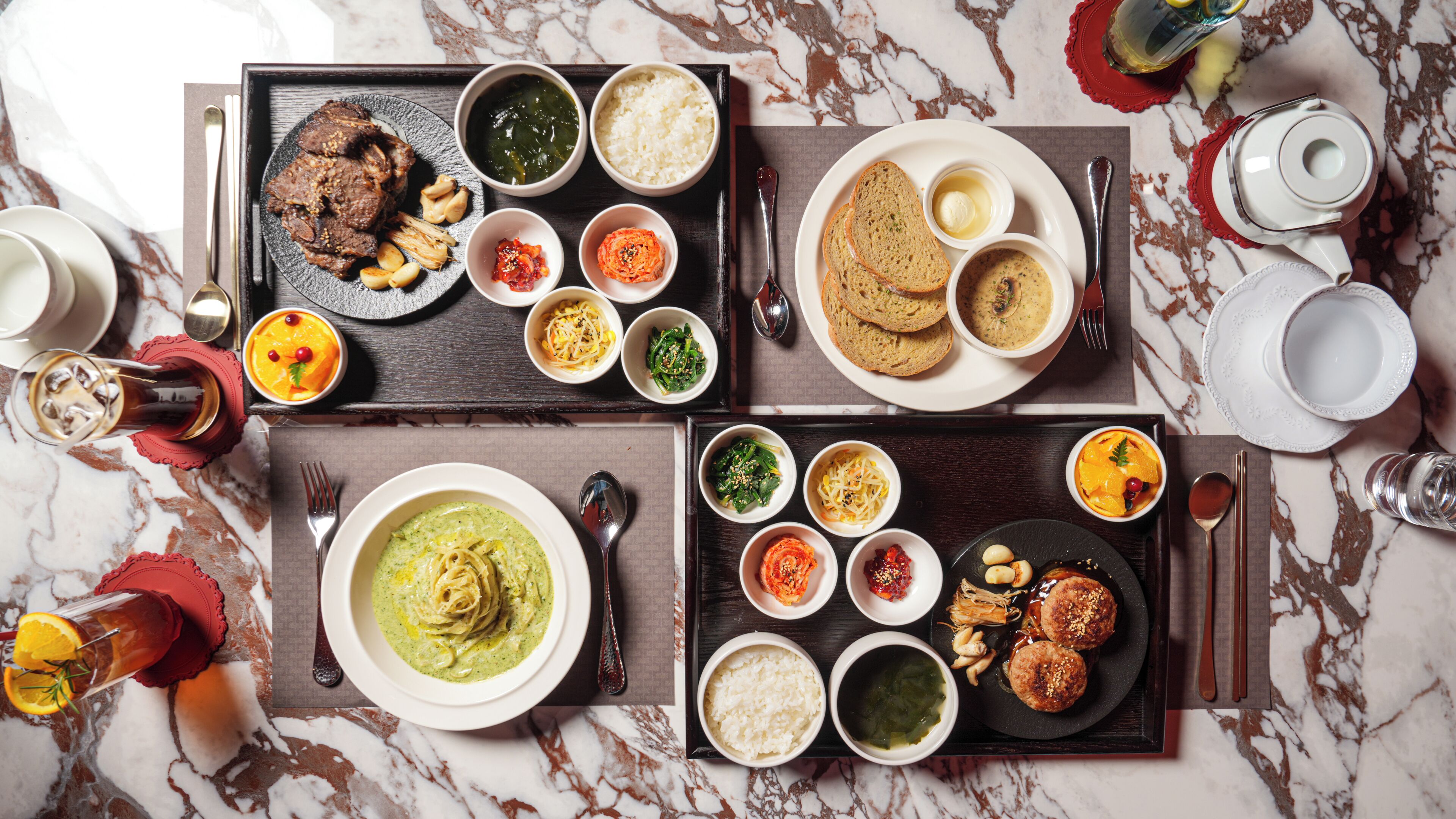 A table set with various dishes, including meat, rice, and soup, on a marble surface.