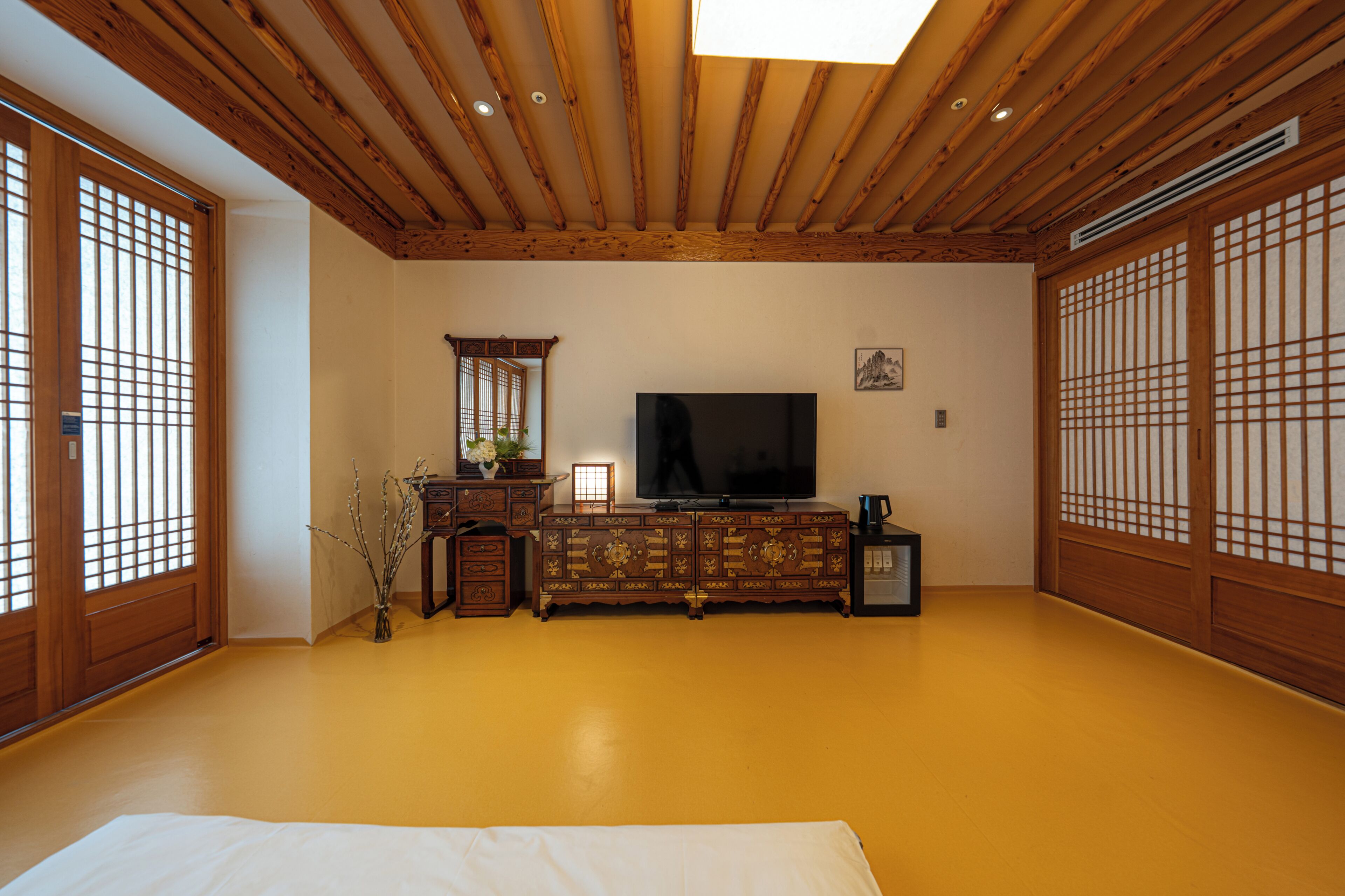 A traditional Japanese-style room with tatami flooring, a television, a cabinet, and sliding doors.