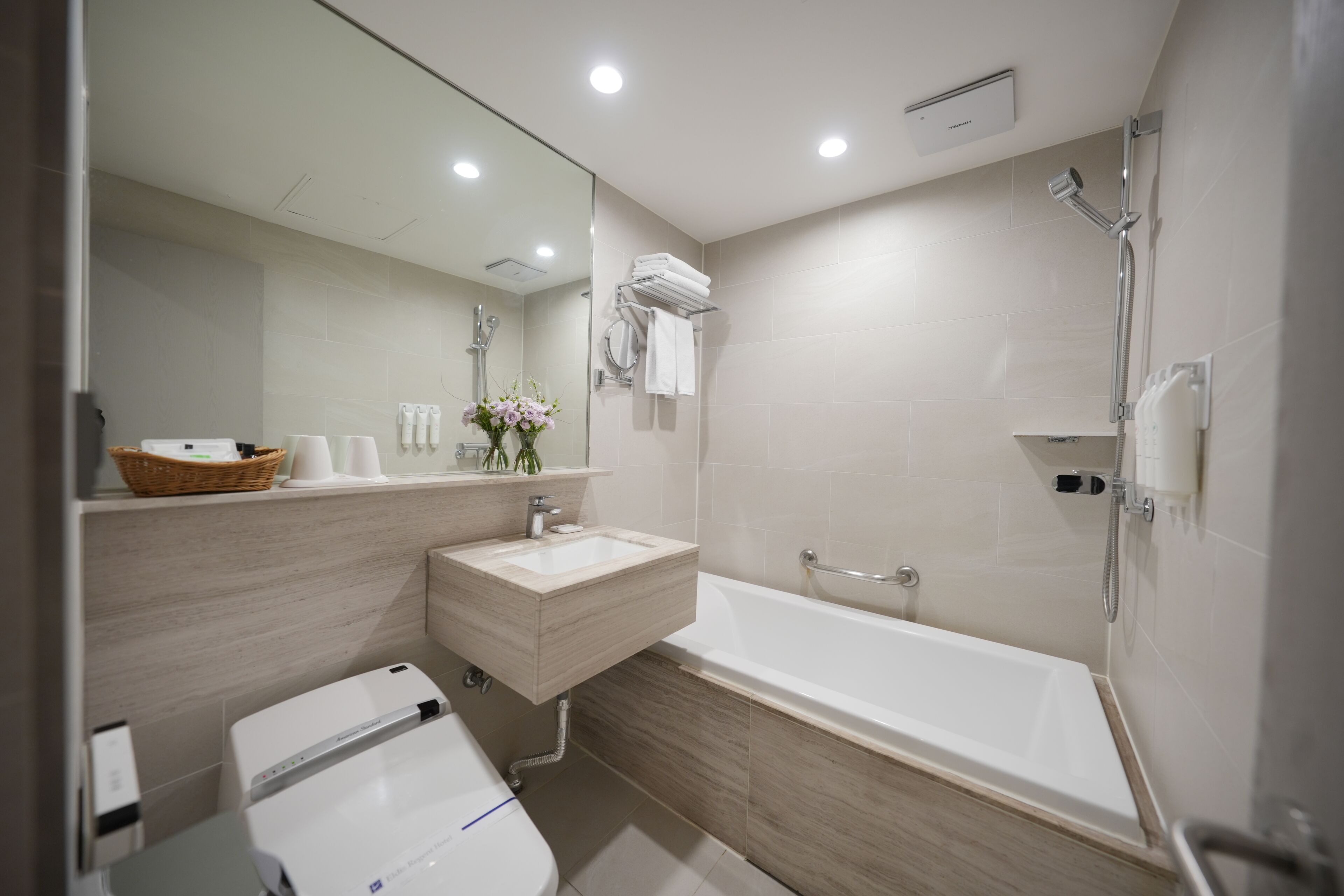 A modern bathroom with a bathtub, a sink, a toilet, and a mirror.