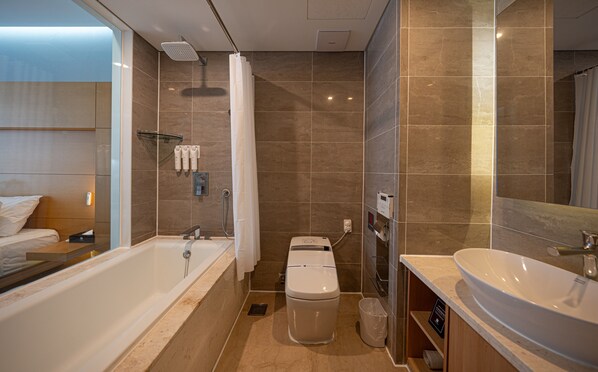 A modern bathroom with a bathtub, toilet, and sink, featuring a showerhead, towel dispenser, and a mirror. - Eldis Regent Hotel (Daegu)