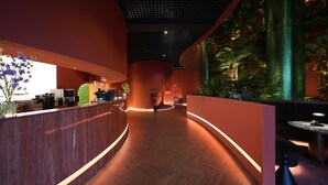 A modern reception area with a curved wooden reception desk, a coffee machine, and a large vertical aquarium. - Eldis Regent Hotel (Daegu)