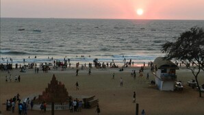 Una playa con un atardecer, gente y una torre de salvavidas.