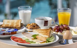 A breakfast tray with toast, eggs, tomatoes, cucumbers, and a glass of orange juice.