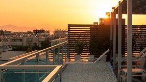 Une terrasse sur le toit avec une piscine, un espace salon et une vue sur le paysage urbain au coucher du soleil.