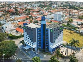 Un hotel moderno con una torre central y dos alas, rodeado por una zona residencial.