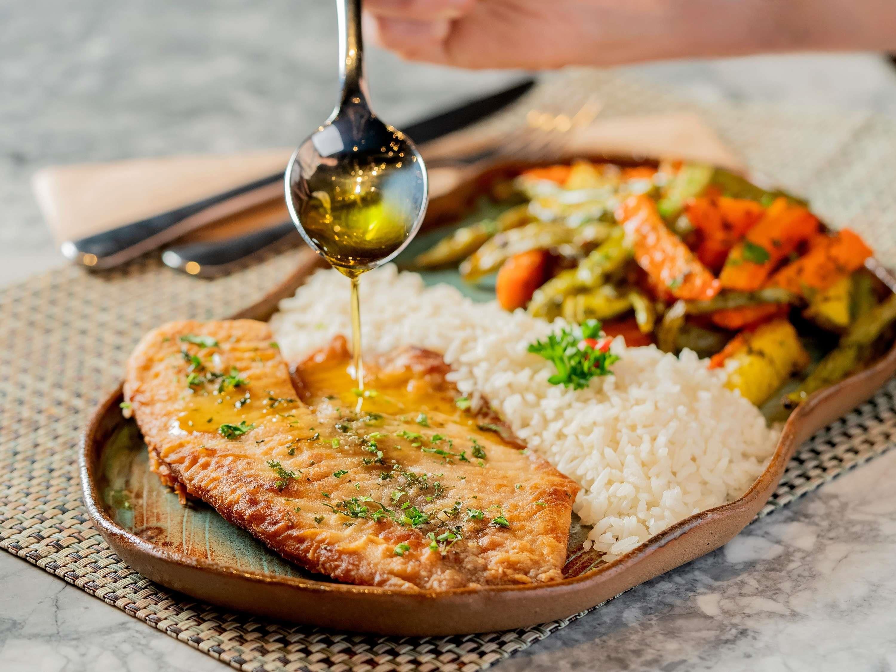 A meal with a piece of fish, rice, and mixed vegetables.