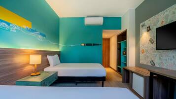 Quarto de hotel com cama, mesa de cabeceira, luminária, ar condicionado, televisão e parede com design de mapa.
