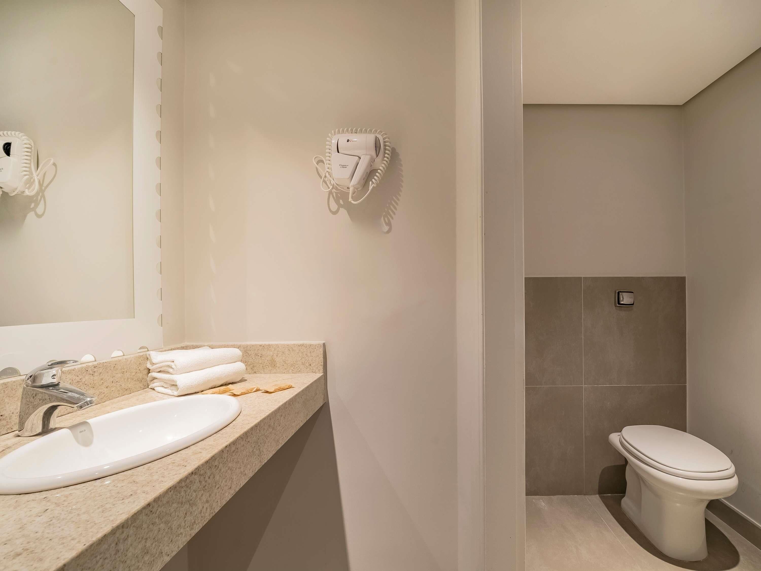 Un baño con lavamanos, toallero y retrete.