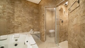 A modern bathroom with a marble wall, a glass-enclosed shower, and a large bathtub. - Ibis Styles Sorocaba Santa Rosalia (Sorocaba)