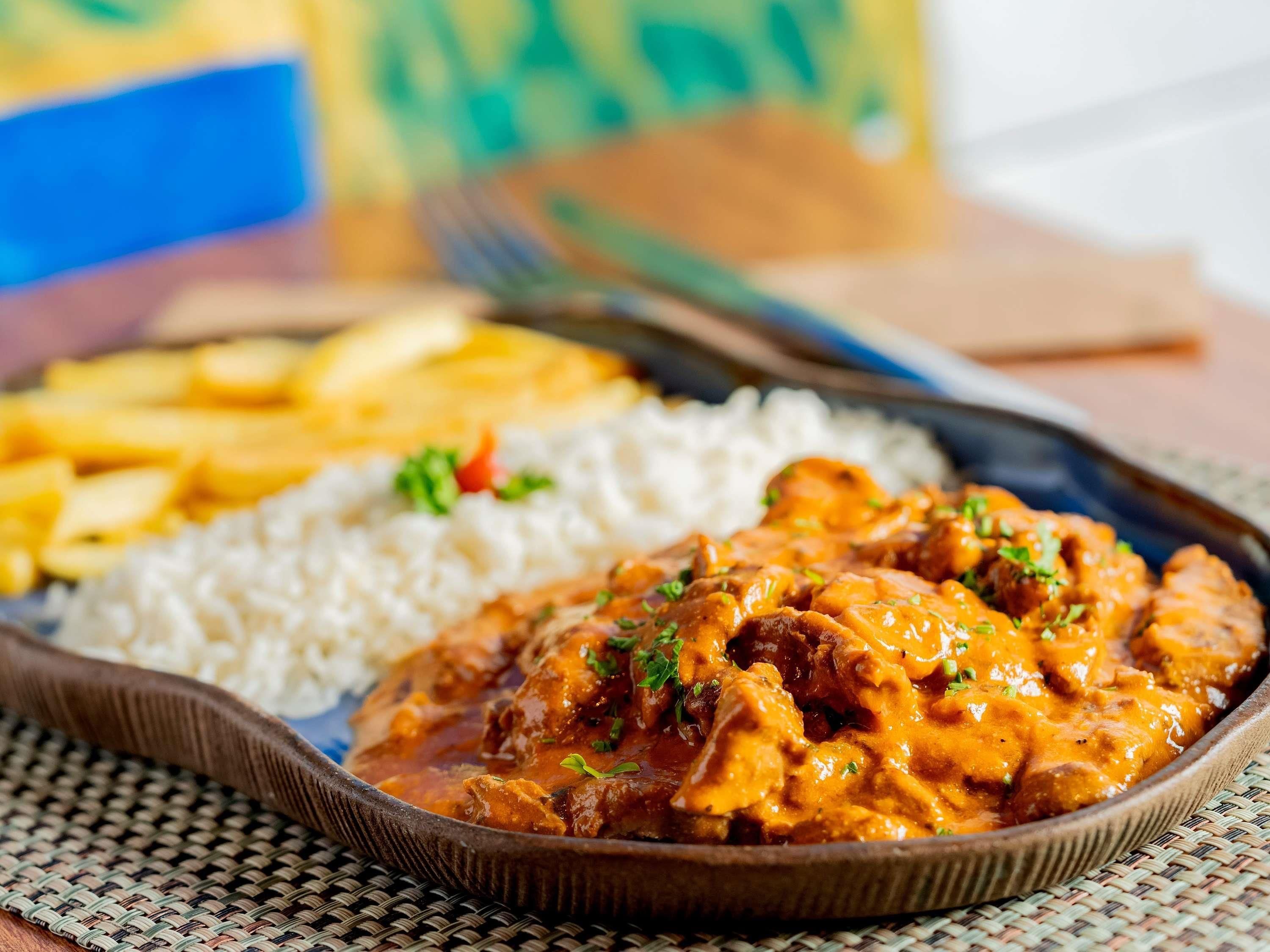 Een bord eten met rijst en een currygerecht, vergezeld van friet.