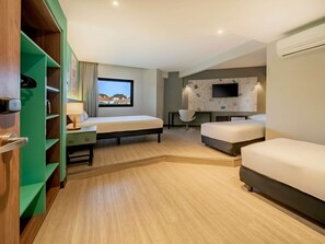 A modern hotel room with a bed, a desk, a chair, a TV, and a window with a view. - Ibis Styles Sorocaba Santa Rosalia (Sorocaba)
