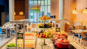 A buffet with various fruits and vegetables, a glass display case, and a red pot on the counter.