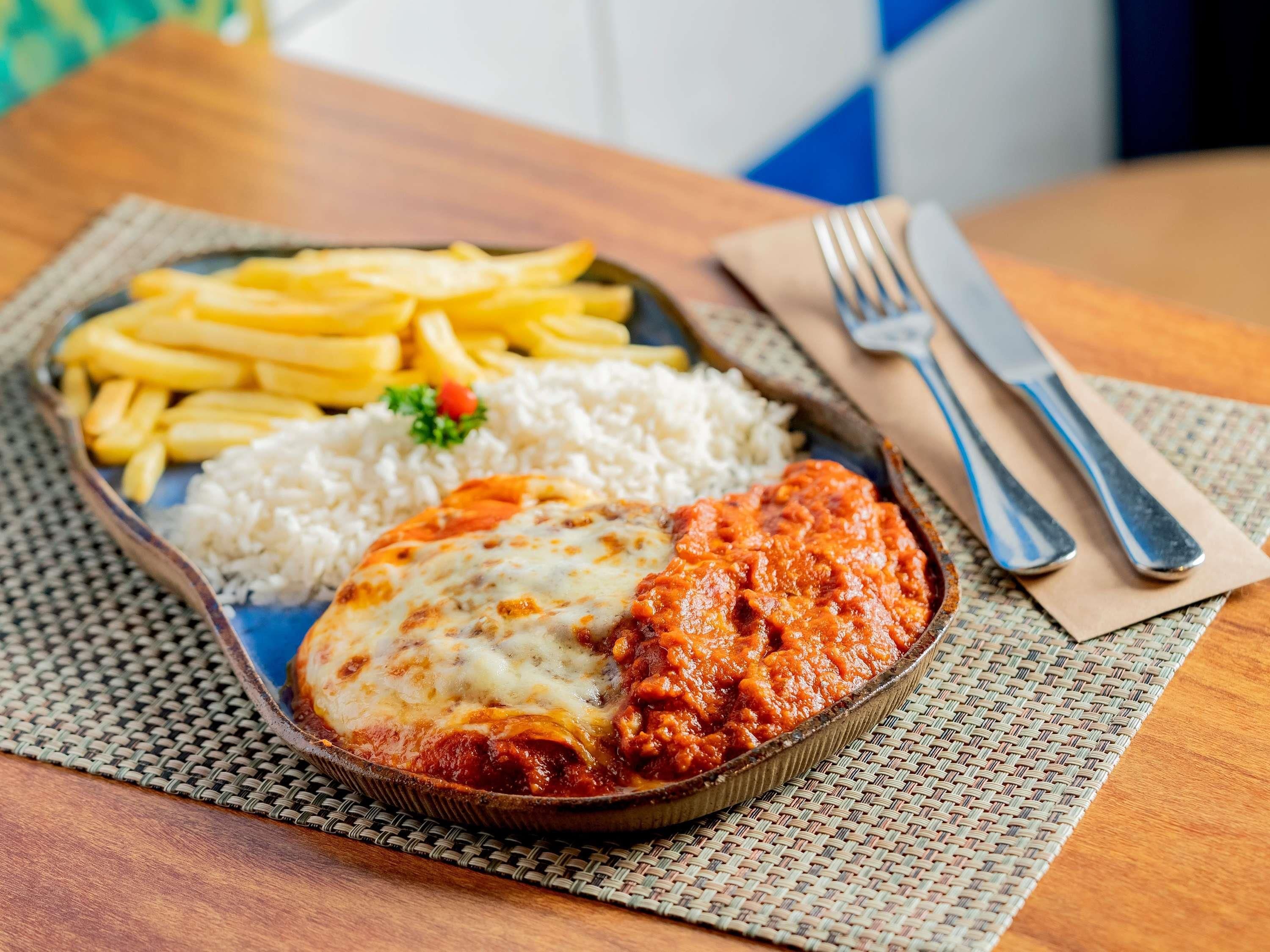 A meal consisting of a baked dish with cheese and tomato sauce, accompanied by white rice and French fries.