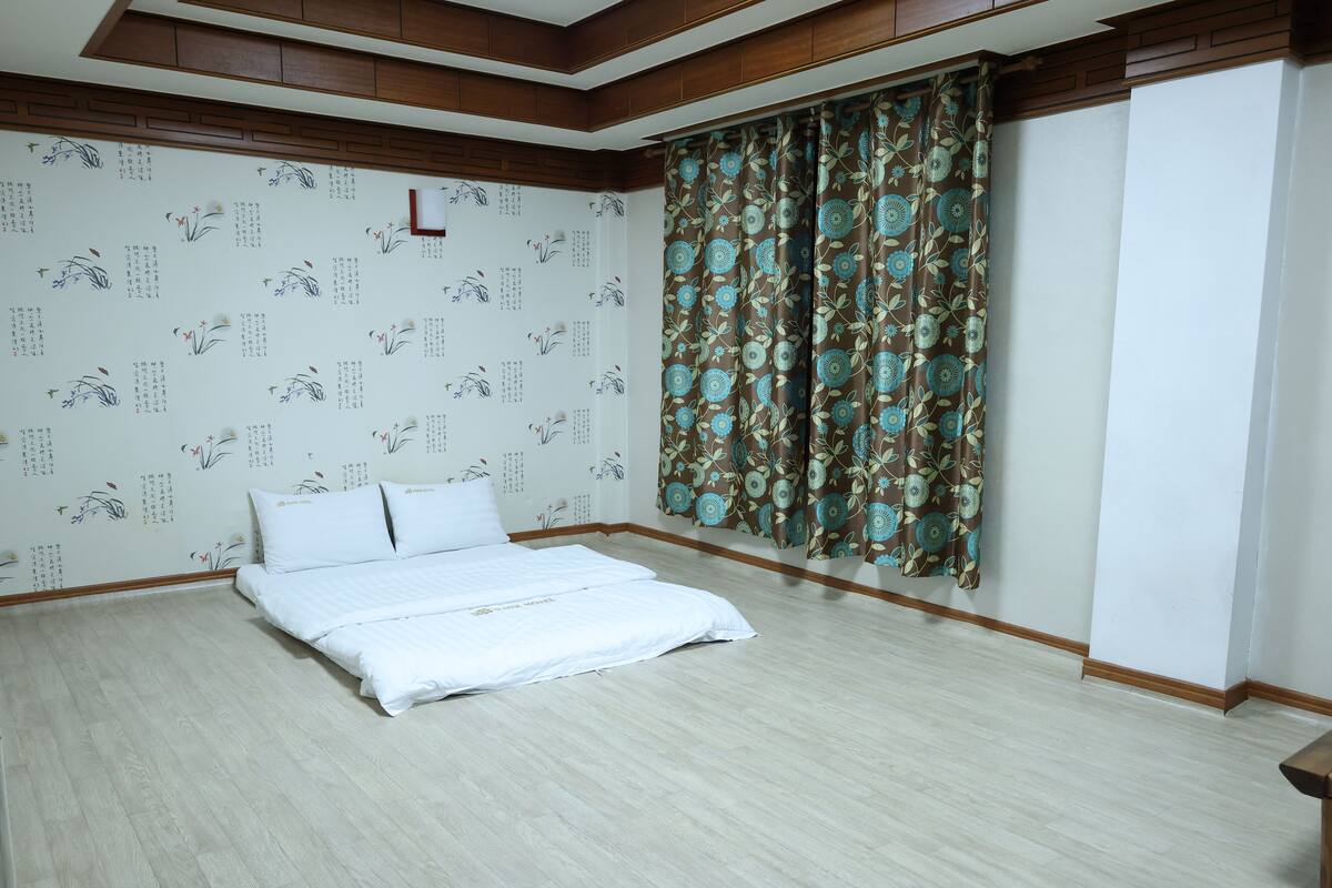 Een hotelkamer met een bed, een houten plafond en een behang met een patroon.