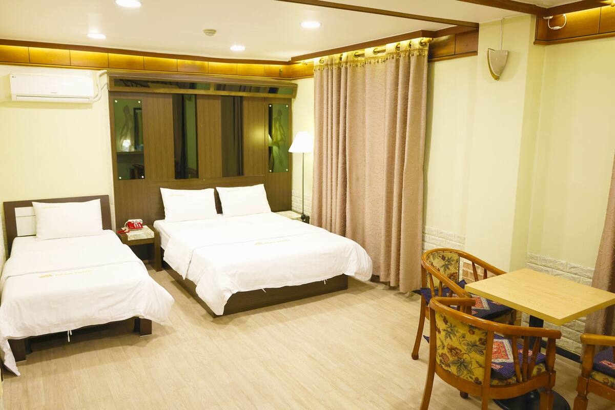 Een hotelkamer met twee bedden, een bureau en een stoel.