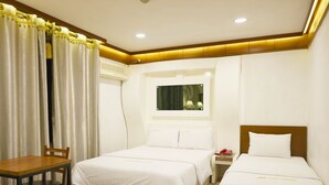 Une chambre d’hôtel avec deux lits, un bureau et une chaise.