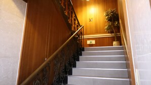 Un escalier en bois avec une rampe en métal, un pot de fleurs et un luminaire.