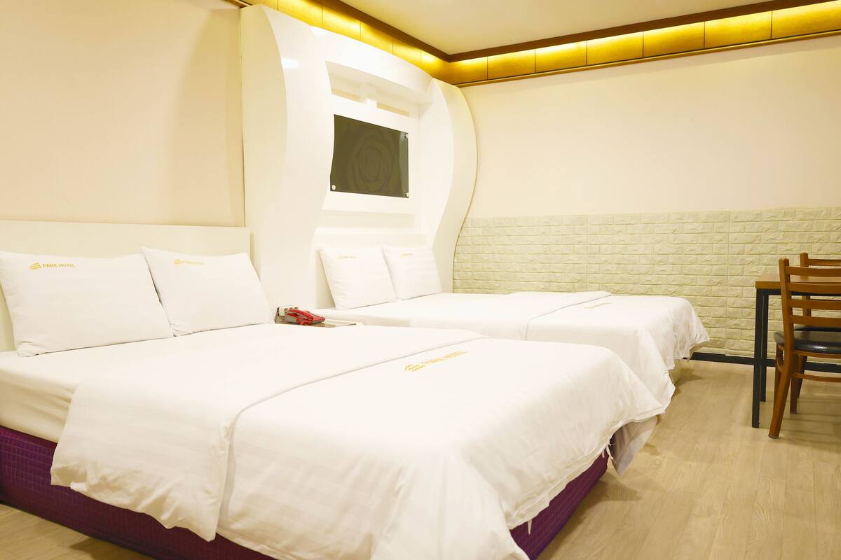 Een hotelkamer met twee bedden, een houten stoel en een muur met een bakstenen patroon.