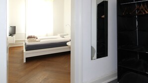 A modern bedroom with a bed, bedside table, and a mirror. - Apartments Spalenring10 (Basel)