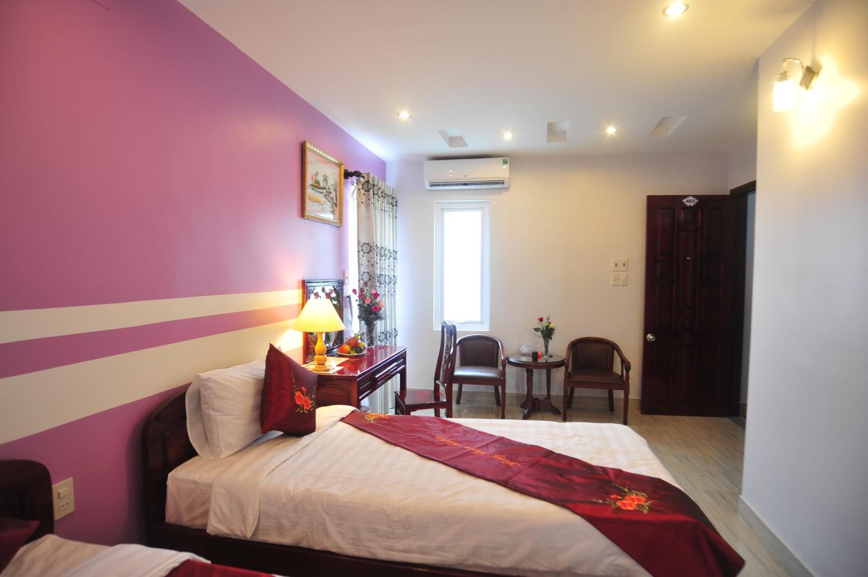 A hotel room with a bed, a desk, a chair, and a small table.