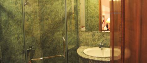 A bathroom with a glass-enclosed shower, a sink, and a toilet.