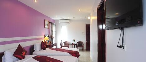 A hotel room with two beds, a TV, a desk with a lamp, and a chair.