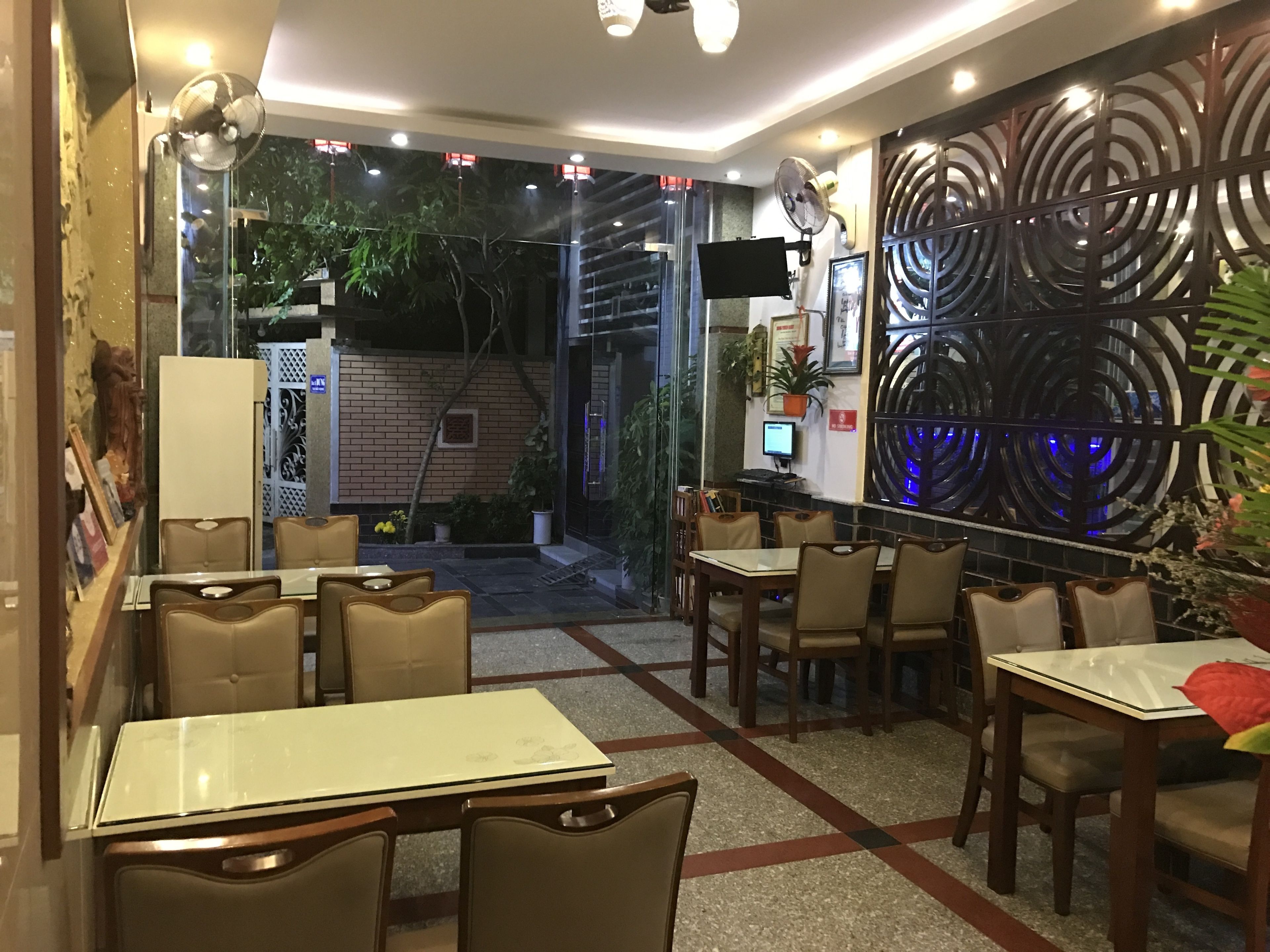 Un restaurante con mesas en el interior, una pared decorativa y vistas al exterior.