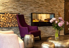 Un área de estar moderna con una pared de piedra, una chimenea y un sillón morado.