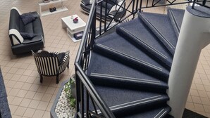 A spacious indoor area with a staircase, seating area, and a reception desk. - Agape Hotel (Bessines)