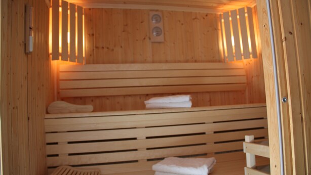 A sauna with wooden benches and benches, and towels placed on them. - Agape Hotel (Bessines)