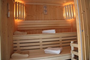 A sauna with wooden benches and benches, and towels placed on them. - Agape Hotel (Bessines)