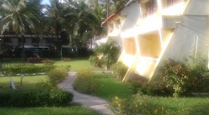 A residential area with a pathway leading to a house with a sloped roof and a visible balcony.