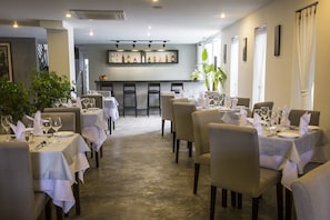 A restaurant with tables set for dining, a bar area, and a view of the street. - G&Z Urban Hotel (Siem Reap)