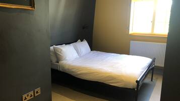 A bedroom with a bed, a window, and a radiator.