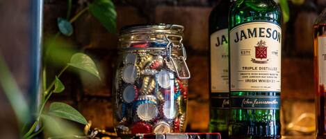 Une bouteille de whisky irlandais Jameson et un bocal rempli de différents bouchons de bouteille.